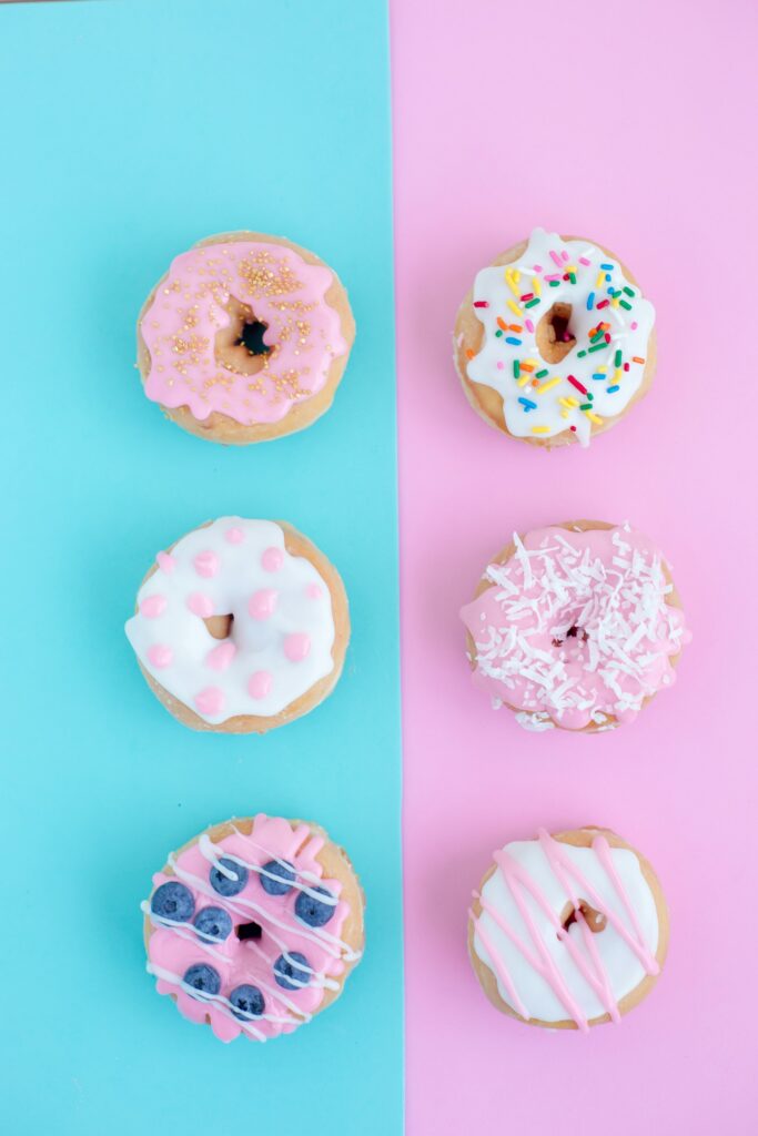 6 donuts colorés sur fond rose et bleu pour illustrer la diversité des plateformes de réseaux sociaux parmi lesquelles il faut choisir
