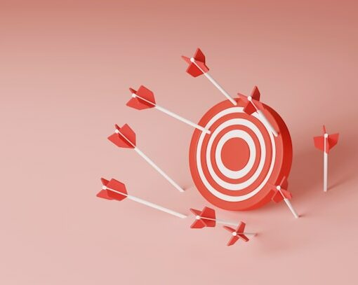 Une cible blanche et rouge avec des fléchettes rouges sur un fond rose bonbon pour illustrer les objectifs de communication