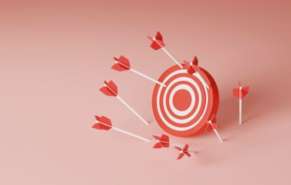 Une cible blanche et rouge avec des fléchettes rouges sur un fond rose bonbon pour illustrer les objectifs de communication