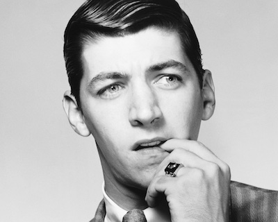 Photographie en noir et blanc d'un homme qui se ronge un ongle et regarde sur le côté l'air de réfléchir entre des choix possibles