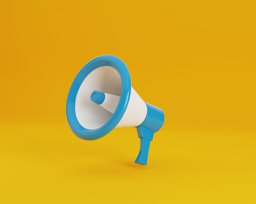 Un porte voix blanc et bleu turquoise sur un fond jaune vif pour illustrer cet article sur la définition du ton et de la voix dans une stratégie de communication